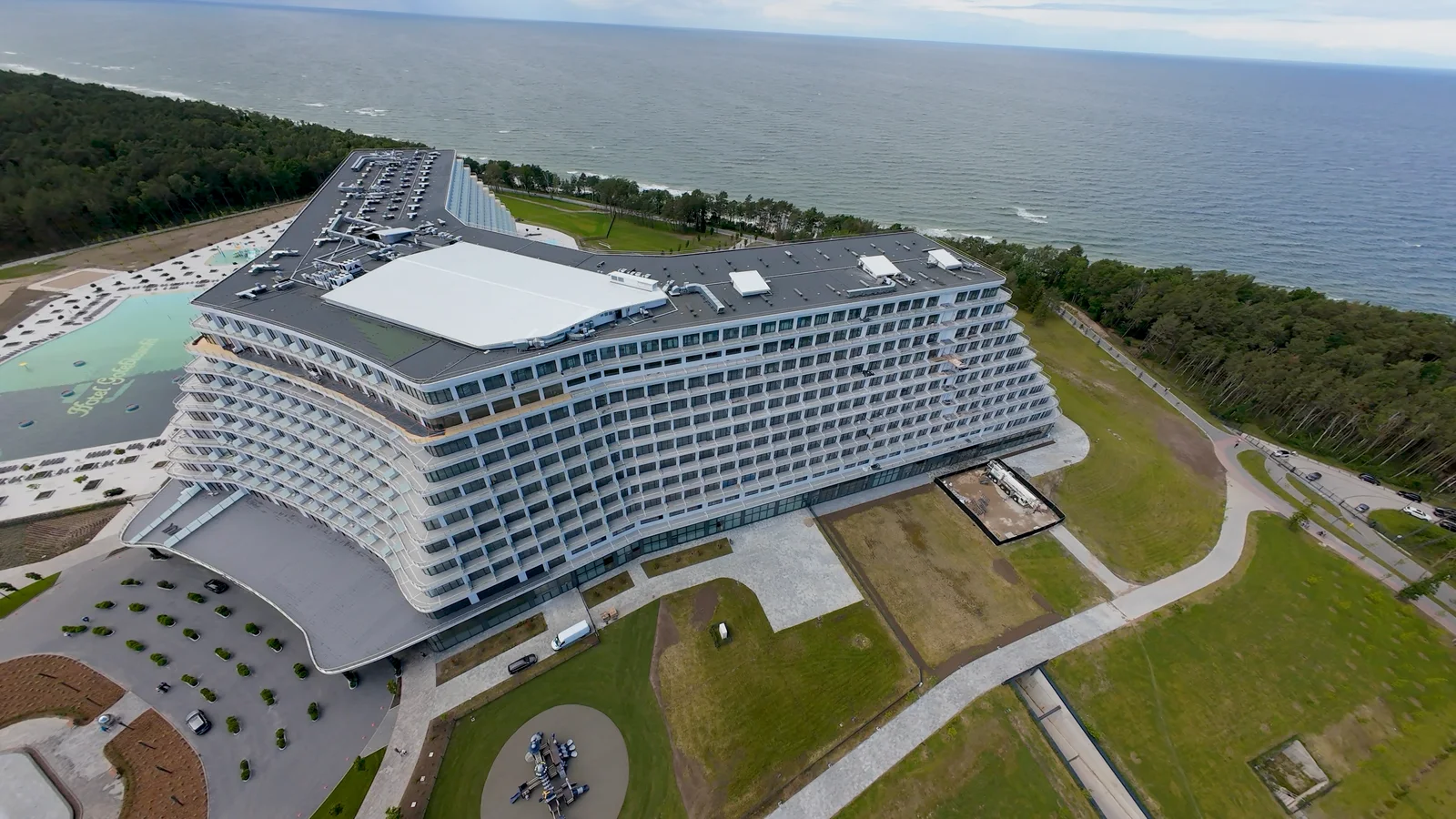 Hotel Gołębiewski w Pobierowie widziany z góry, z lasem i Morzem Bałtyckim w tle.
