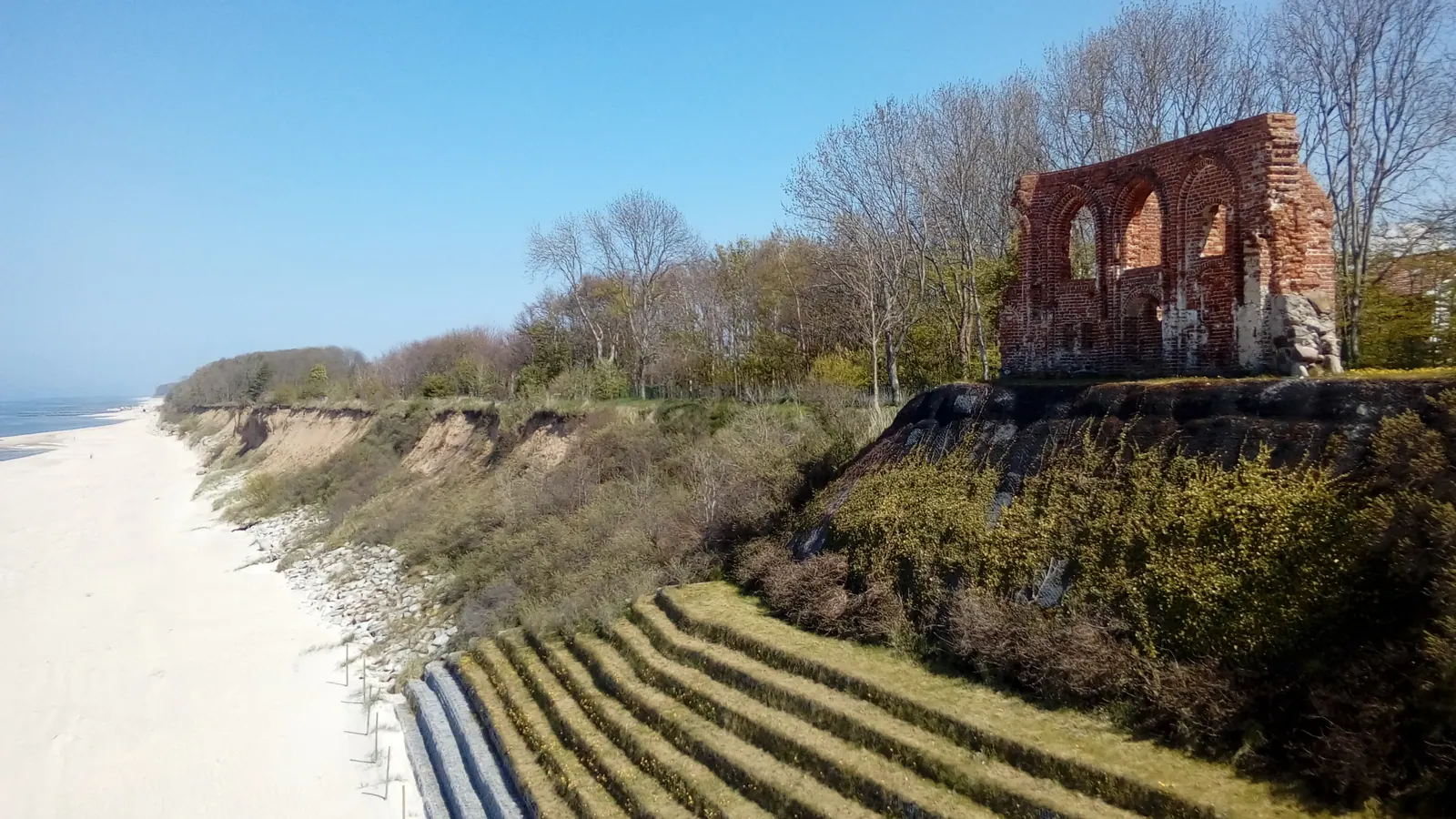 Klif w Trzęsaczu z ruinami kościoła nad plażą i Bałtykiem.